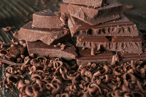 Shavings and pieces of tasty milk chocolate on table, closeup