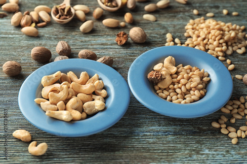 Plates with different nuts on wooden background