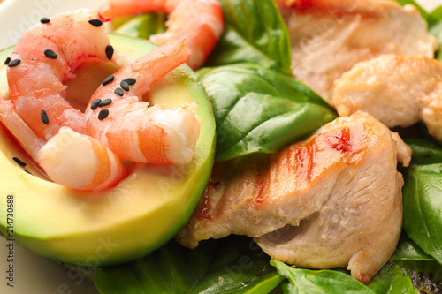 Salad with ripe avocado, chicken and shrimps on plate, closeup