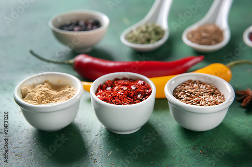 Bowls with different spices on color background