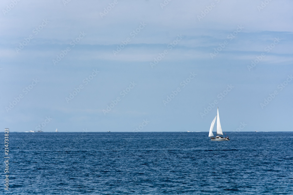 Sailboat glides across the bright blue ocean