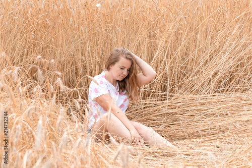 Blond girl in gold wheaten field. Unity with nature, freedom, happiness..