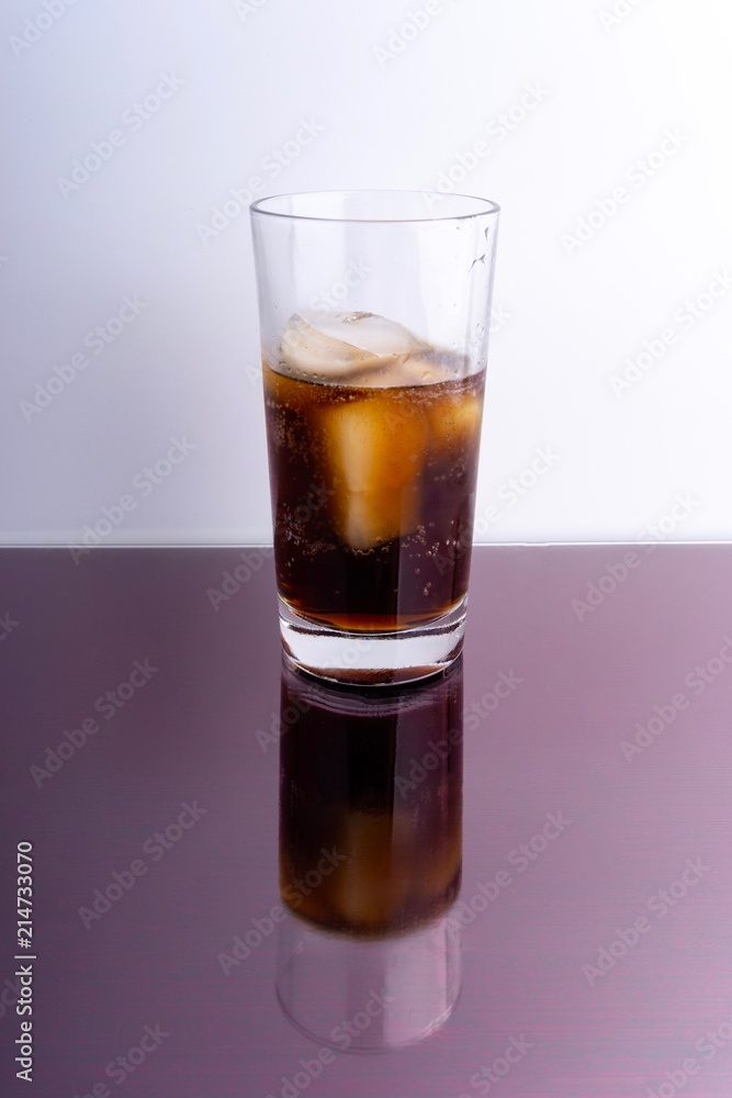 Cola and ice cubes in glass on white background with selective focus and crop fragment Cola and ice cubes in glass on white background with selective focus and crop fragment
