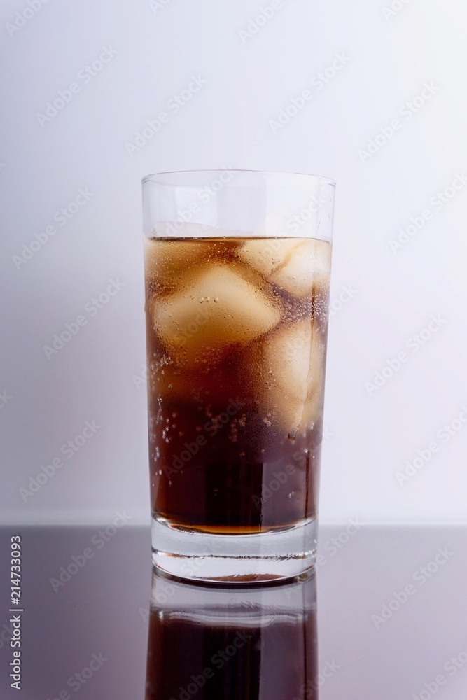 Cola and ice cubes in glass on white background with selective focus and crop fragment Cola and ice cubes in glass on white background with selective focus and crop fragment