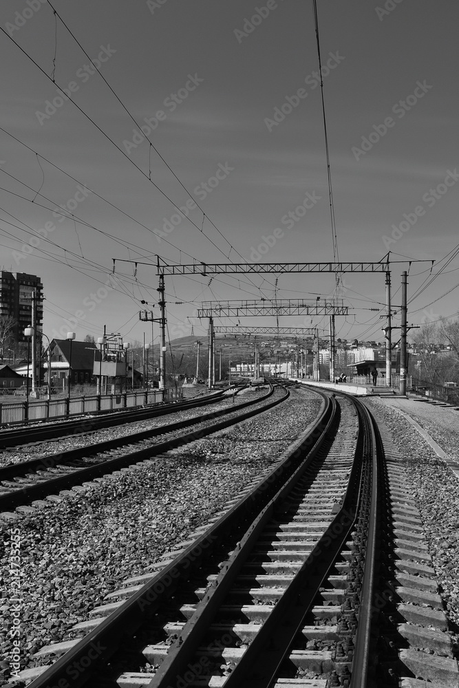 Railway tracks in front of the station, Prague. High contrast, black and white image. Electrical wires on supports
