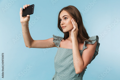 Portrait of a lovely young woman in dress taking a selfie