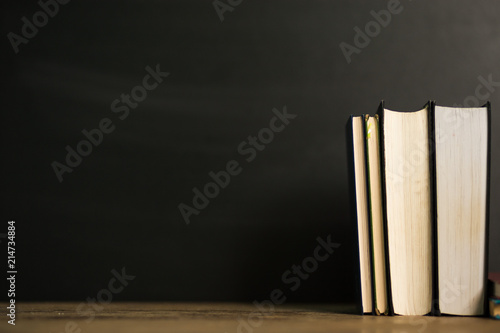 Stack old hardback books on wooden deck table and dark background