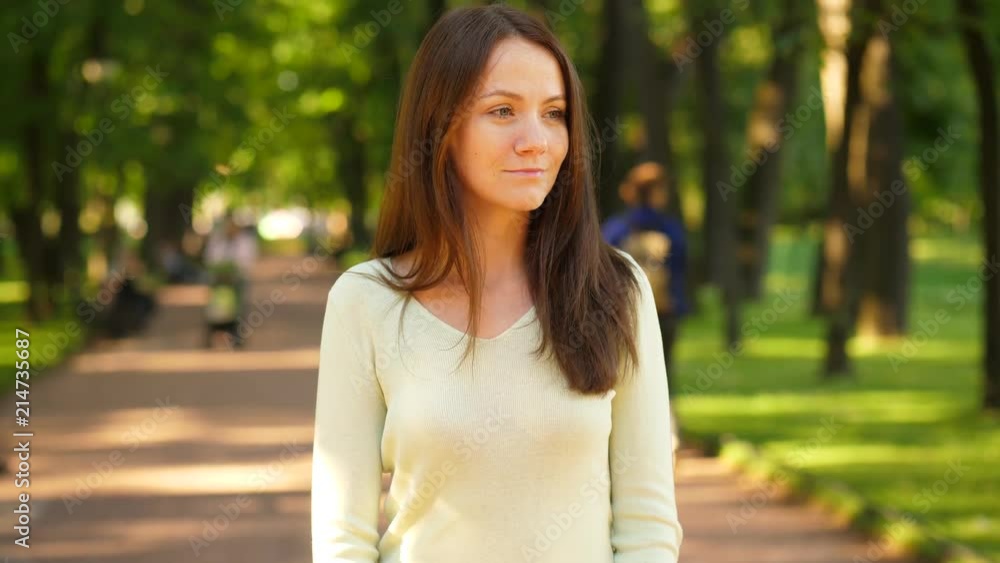 Portrait of sad woman standing alone in summer park Portrait of sad woman standing alone in summer park