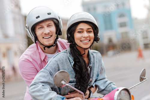 Bright experience. Merry optimistic couple wearing helmets and looking at camera