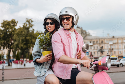 New member. Jovial gay woman carrying plant and man riding on motorbike