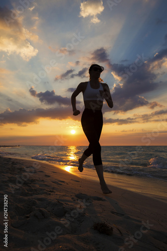 Woman running on the beach during a beautiful sunset.