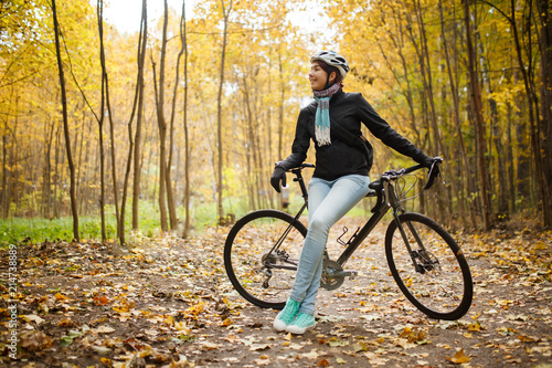 Picture of girl in helmet  jeans next to bicycle in autumn park