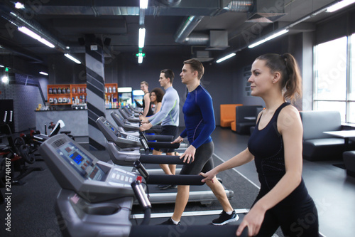 Young people running on treadmill in gym