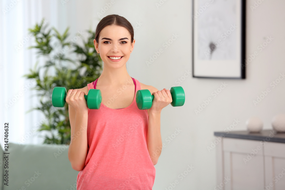 Beautiful young woman training with dumbbells at home in morning Beautiful young woman training with dumbbells at home in morning