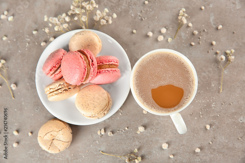 Flat lay composition with tasty macarons and cup of coffee on grey background