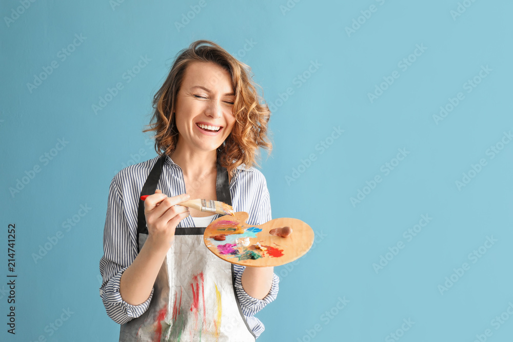 Female artist with brush and paint palette on color background Female artist with brush and paint palette on color background