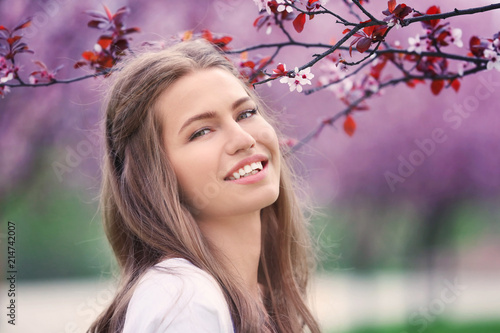 Beautiful young woman near blossoming tree on spring day