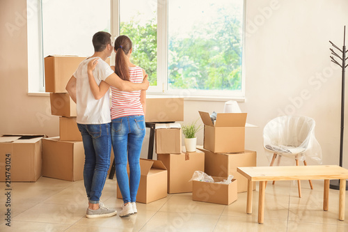 Young couple standing near boxes indoors. Moving into new house © Pixel-Shot
