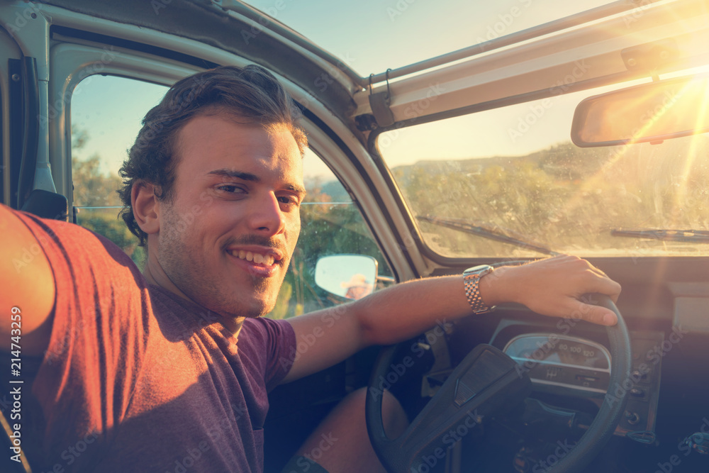 Fototapeta premium Young man in a car at sunset