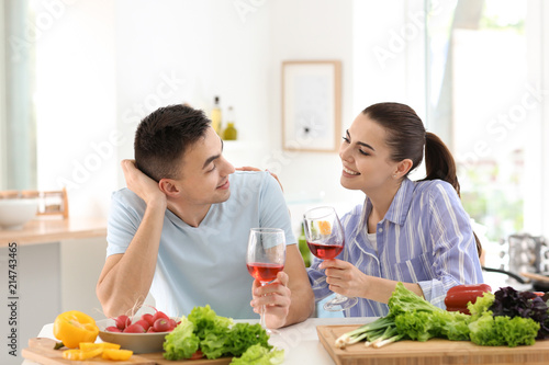 Young couple drinking wine while cooking together in kitchen