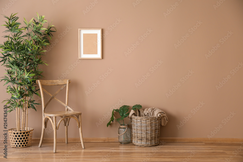 Wooden chair with wicker basket and plant near color wall - obrazy, fototapety, plakaty 