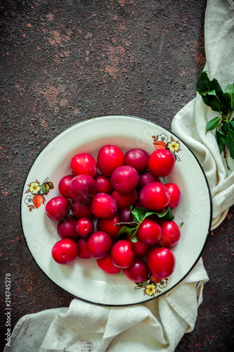 Fresh red plum with leaves on a wooden dark background
