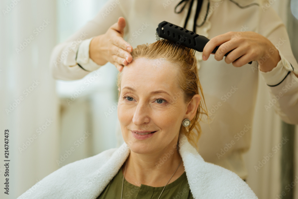 Fototapeta premium Pleasant emotions. Portrait of a beautiful blonde woman smiling while being in the beauty salon