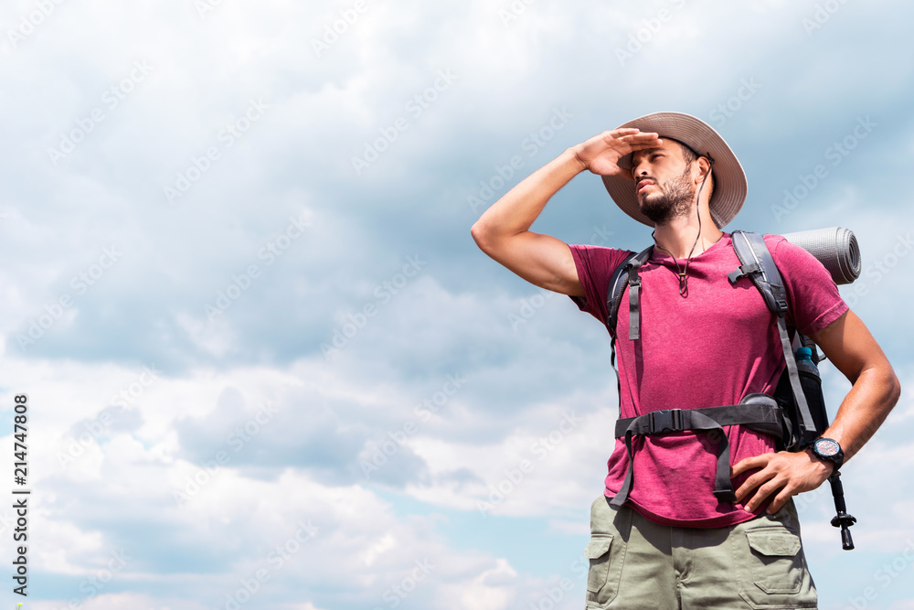 handsome tourist in hat looking away, with cloudy sky background handsome tourist in hat looking away, with cloudy sky background