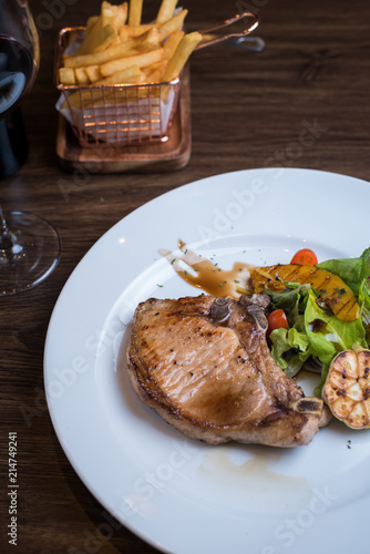 Grilled pork steak. Delicious grilled pork chops with strips sprinkled with fresh coriander served on white plate,
