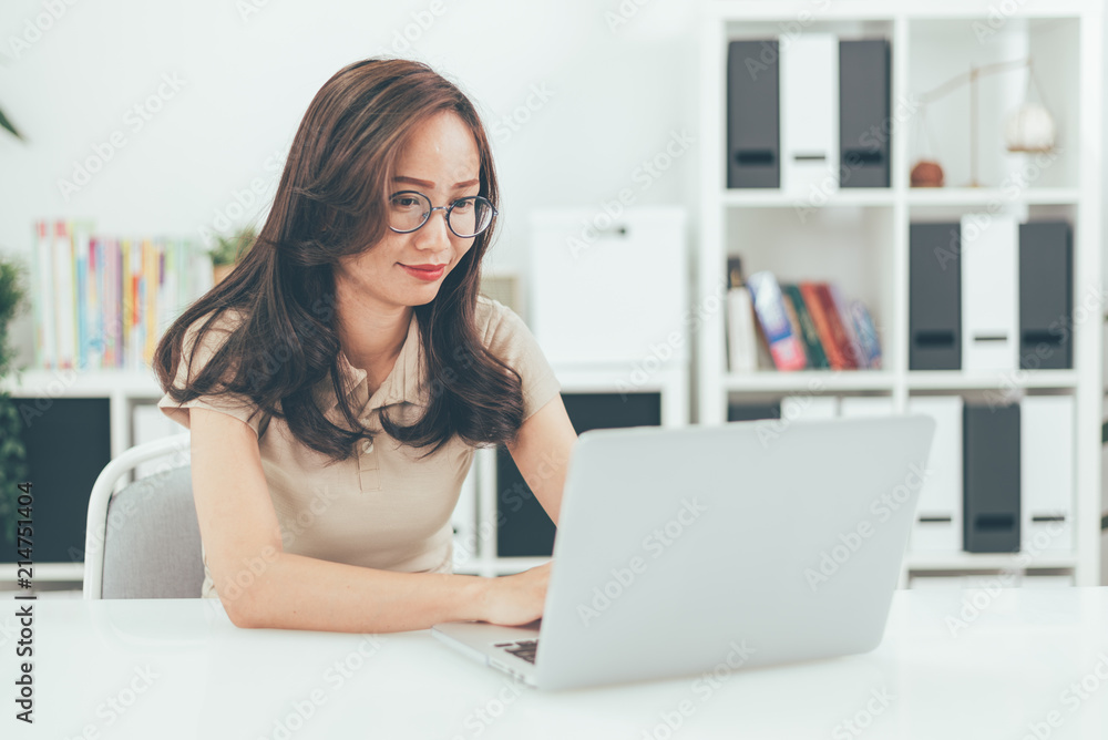Happy young businesswoman with glasses working on computer laptop in home office Happy young businesswoman with glasses working on computer laptop in home office
