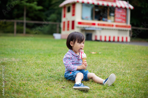 baby girl sitting on summer meadow and eating icecream