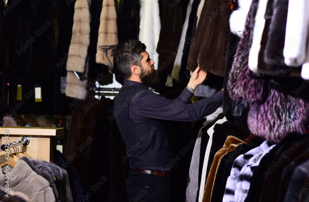 Guy looks at fur coat. Luxury shopping concept.