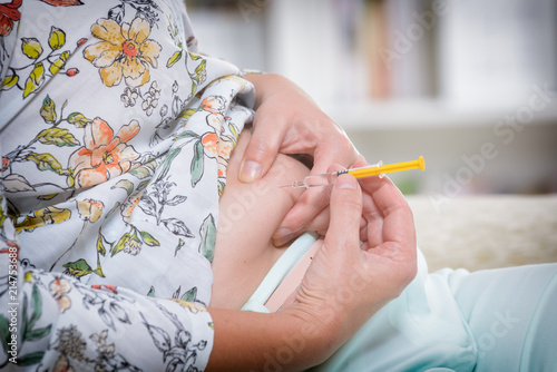 Woman is doing an insulin or heparin injection photo