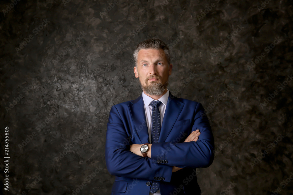 Handsome mature man in elegant suit on dark textured background Handsome mature man in elegant suit on dark textured background