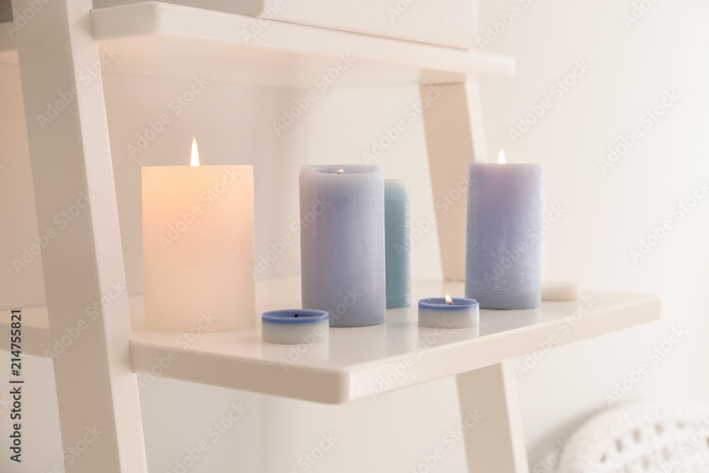 Burning wax candles on shelf