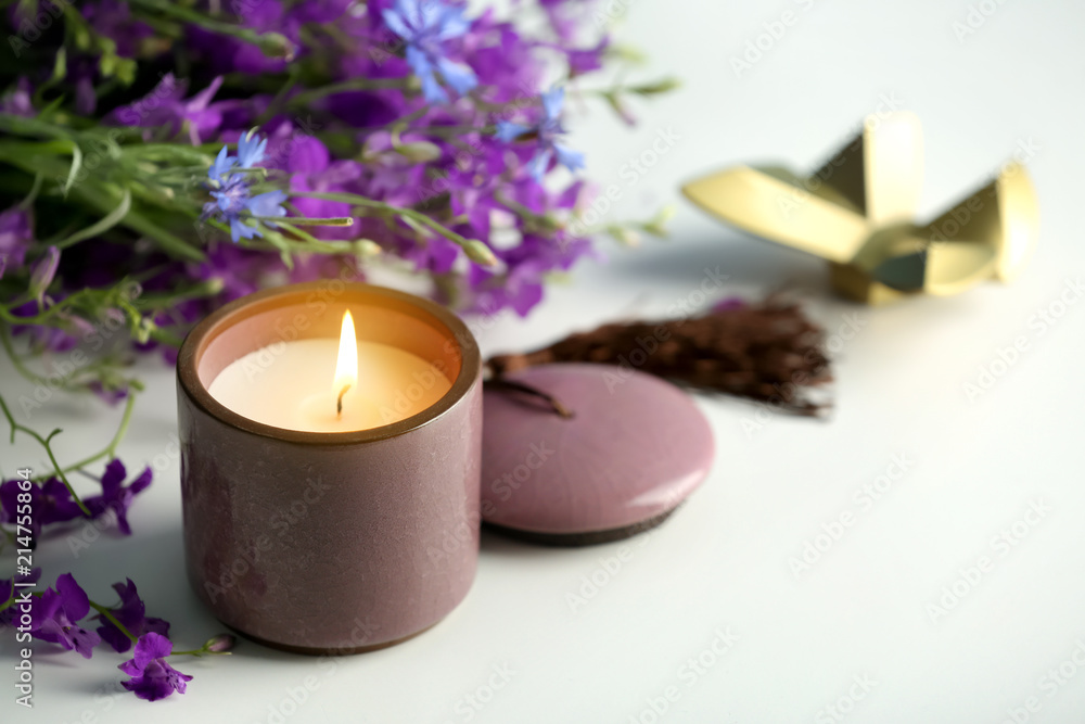 Burning candle and beautiful flowers on white table Burning candle and beautiful flowers on white table