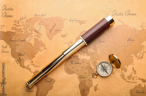 Spyglass and compass on vintage world map. Travel planning concept