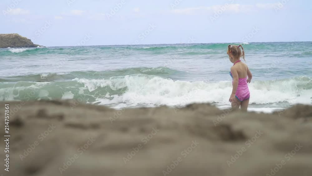 little girl walk down the beach in the waves on a beautiful day little girl walk down the beach in the waves on a beautiful day