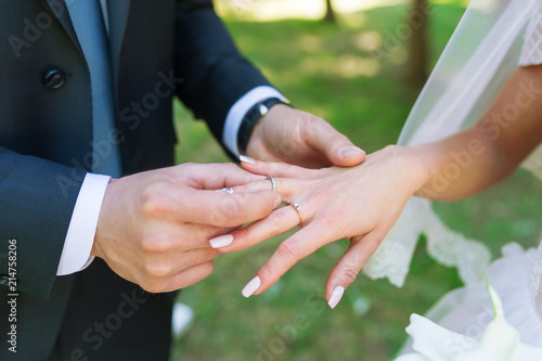 Closeup of the groom placing a wedding ring on the brides hand.