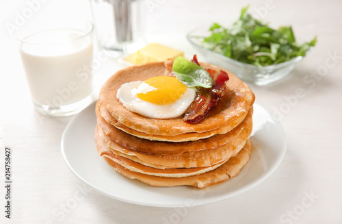 Plate with tasty pancakes, fried egg and bacon on wooden table