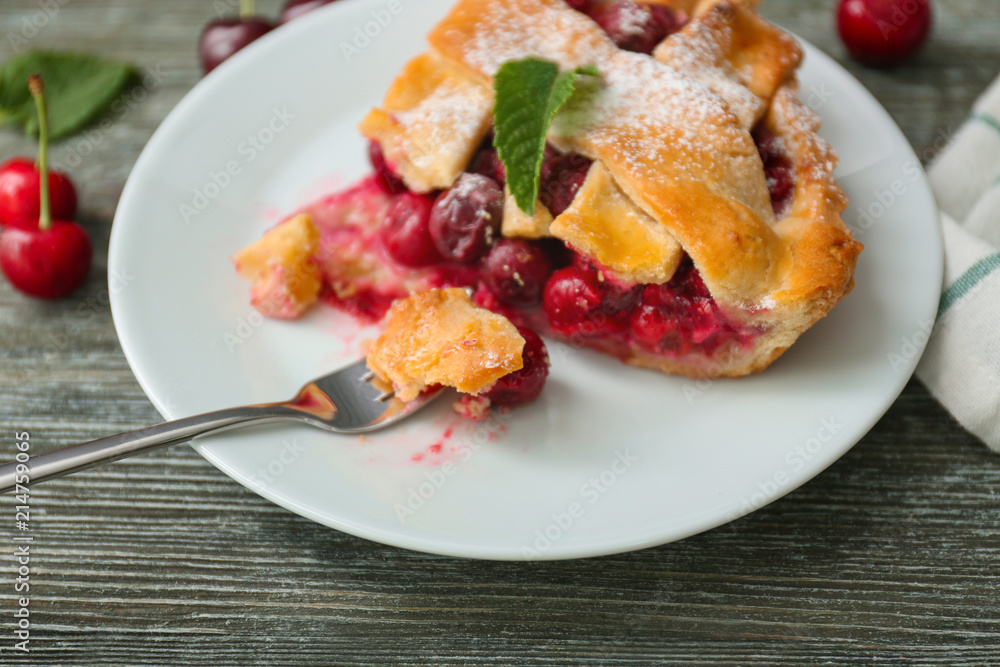 Plate with piece of delicious cherry pie on wooden table, closeup