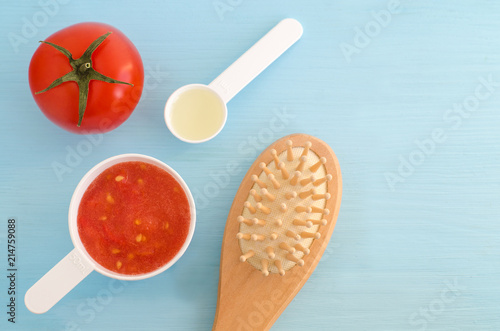 Plastic scoops with tomato puree, olive oil and wooder hair brush. Ingredients for preparing homemade hair mask. DIY cosmetics recipe. Top view, copy space.