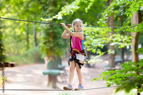 Child in adventure park. Kids climbing rope trail. photo