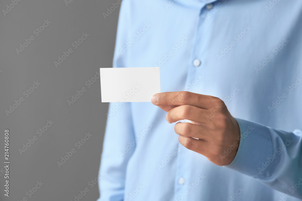 Man with business card on grey background, closeup Man with business card on grey background, closeup