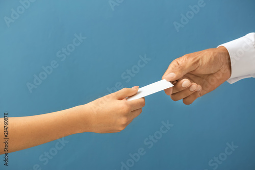 Man giving business card to woman on color background