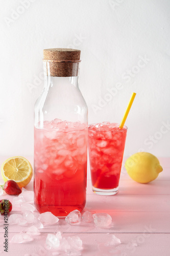 Bottle and glass with tasty strawberry lemonade on table