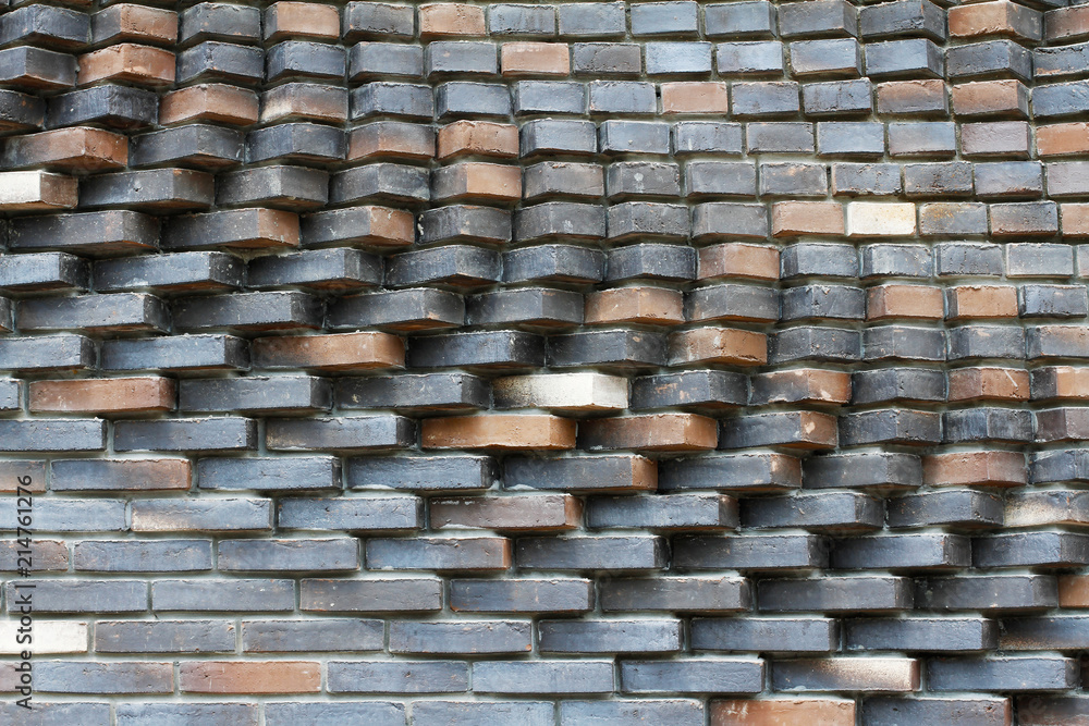 Colorful (grey, beige, black, orange and brown) relief brick wall as background, texture