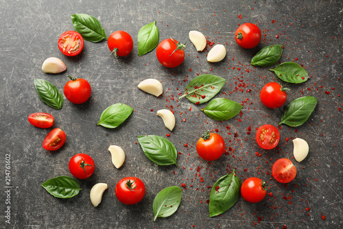 Composition with fresh cherry tomatoes, basil and garlic on grey background