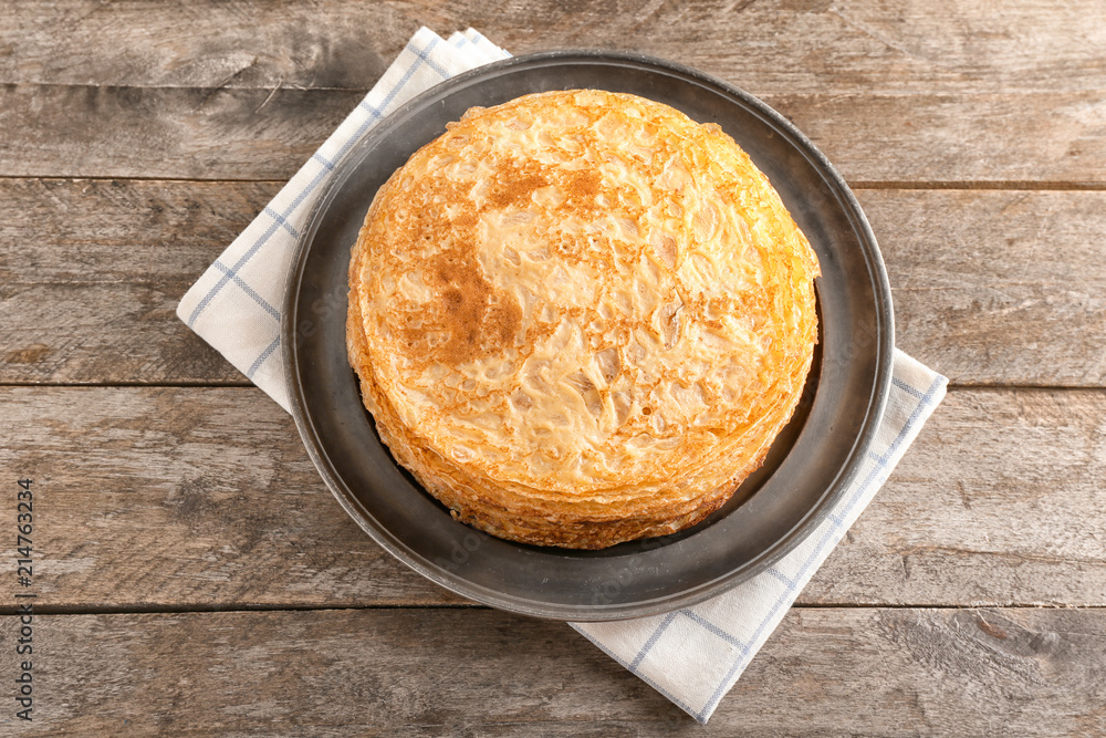 Plate with stack of tasty thin pancakes on wooden table Plate with stack of tasty thin pancakes on wooden table