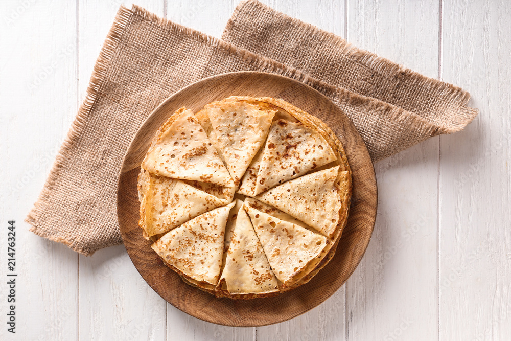 Wooden board with tasty thin pancakes on table Wooden board with tasty thin pancakes on table